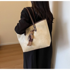 Détail du sac cabas beige minimaliste avec bandoulière marron et pendentif lapin