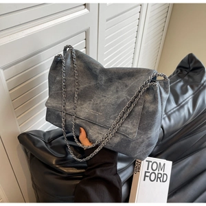 Detail of dark grey leather flap bag with metal chain strap and subtle logo texture