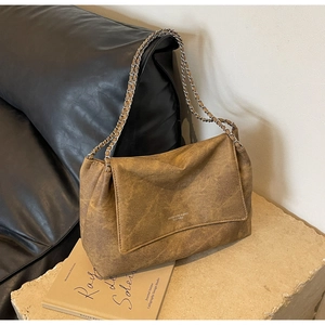 Detail view of retro brown textured leather tote bag with elegant silver chain shoulder strap
