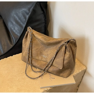 Detail of vintage brown leather texture and silver chain strap on a large tote bag