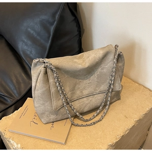 Detail of taupe chain shoulder bag with matte texture and embossed logo on flap
