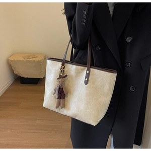 Détails de la texture craquelée du sac cabas crème avec ses anses marron contrastées