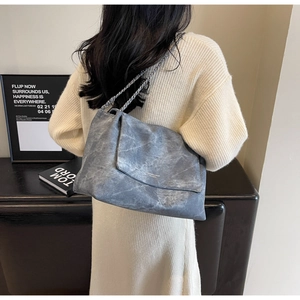 Detail of grey-blue stone texture shoulder bag with silver chain strap and flap closure