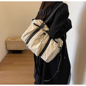 Detail einer großen beigen Reisetasche mit Kordelzug-Falten und schwarzen Schultergurten