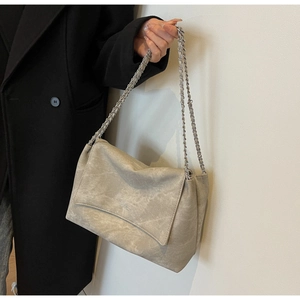 Detail of grey vintage leather tote bag with chain strap on a black wool coat