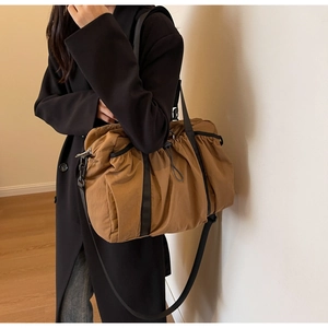 Detail der braun gerafften Reisetasche mit schwarzen Trägern und Nylon-Gewebe-Struktur