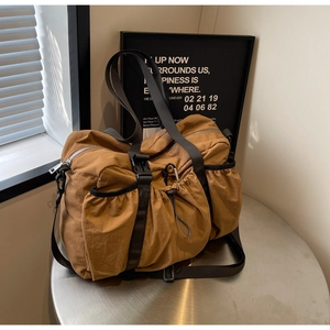 Detailansicht der khakifarbenen Reisetasche mit Kordelzugtaschen und Schnallen auf Metalltisch