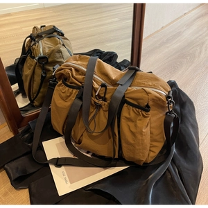 Detail der khakifarbenen Nylontasche mit Kordelzugtaschen und schwarzen Tragegriffen