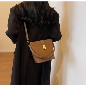Détail du sac seau marron avec fermoir tournant doré et texture en daim mat