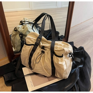 Details der beigen Reisetasche aus Nylon mit schwarzen Schnallen und Kordelzugtasche