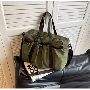 Detail der olivgrünen Reisetasche mit Kordelzugtasche auf schwarzem Ledersofa