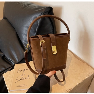 Détail du sac seau en daim marron avec poignée ronde et fermoir en métal doré chic