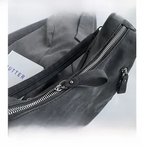 Detailed macro view of smooth silver metal zippers on a gray suede tote bag surface