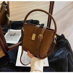 Détail du sac seau vintage en cuir givré marron avec boucle en métal et poignée