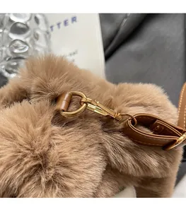 Close-up of golden metal hardware hooks on plush faux fur handbag with leather strap