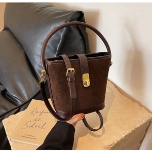 Détail du sac seau marron foncé avec texture en daim mat et fermoirs métalliques dorés