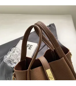 Détail du sac seau en cuir grainé marron avec boucle en métal doré et poignée élégante