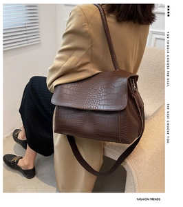 Détail d'un sac à bandoulière en cuir marron foncé à motif crocodile avec rabat