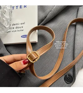 Close-up of adjustable brown leather shoulder strap with gold buckle on plush bag