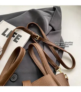 Détail de la bandoulière réglable et boucle dorée sur le sac seau en cuir grainé marron