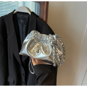 Close-up of silver pleated chain bag with pearl charms on a black suit jacket
