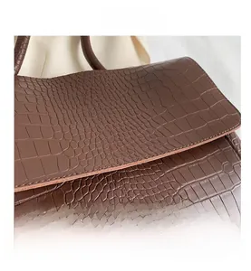 Gros plan détaillé du sac à main marron foncé avec texture crocodile et coutures soignées