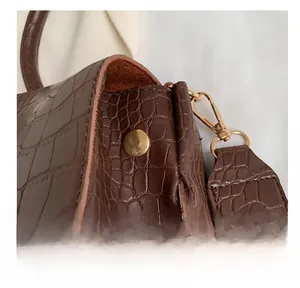 Détail du cuir gaufré crocodile marron foncé et du crochet en métal doré de luxe