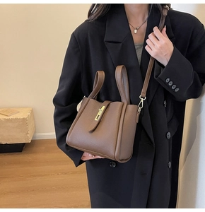 Détail d'un sac à main en cuir marron café avec fermoir doré porté par un mannequin