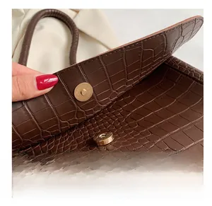 Détail du fermoir magnétique sur le sac fourre-tout marron foncé à motif crocodile