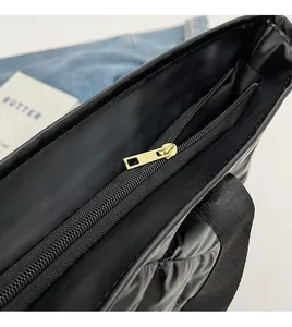 Close-up of golden metal zipper and quilted texture on a black tote bag