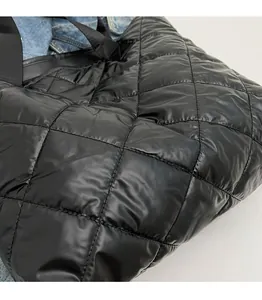 Detail of black quilted puffer tote bag showing soft glossy fabric and stitch pattern