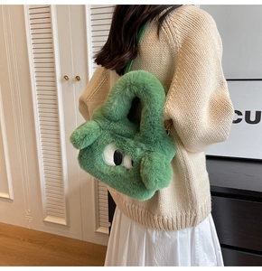 Detail of green plush crossbody bag with cartoon monster eyes worn by a model
