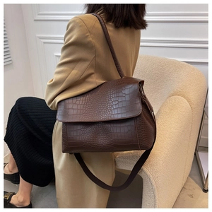 Détail du grand sac à bandoulière marron motif crocodile porté avec un blazer marron