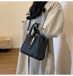 Détail du sac seau noir grainé avec fermoir métallique et texture cuir sur un mannequin