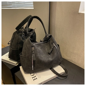 Detail view of large charcoal gray suede tote bag with dual front zippers and side pockets
