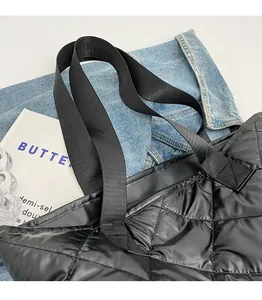 Detail of black quilted tote bag showing wide fabric handles and smooth zipper closure