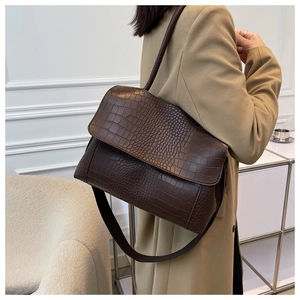 Sac fourre-tout marron foncé effet crocodile porté sur un manteau en laine kaki
