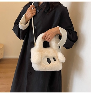 Detail of soft white faux fur bag featuring large cartoon eyes and a slender shoulder strap