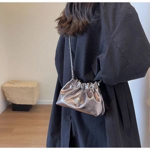 Silver metallic dumpling bag with chain strap and pearl charm on a black coat