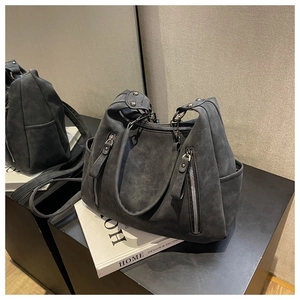 Detail of dark gray tote bag showing matte texture, side zipper, and reinforced handle