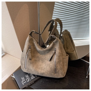 Detailed macro shot of vintage brown hobo bag with dual vertical metal zippers and matte leather