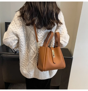 Détail du sac seau en cuir caramel avec fermoir doré et texture en cuir grainé fin