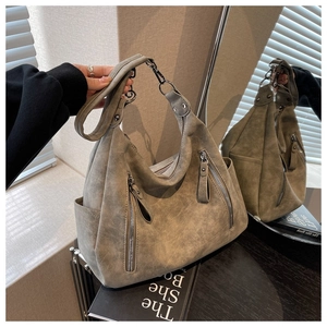 Detail of grey large capacity tote bag with metal zippers and textured faux leather surface