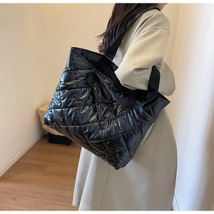 Detailed view of the large black quilted tote bag with glossy finish and wide shoulder strap