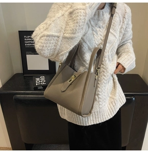 Détail du sac seau en cuir gris éléphant avec fermoir doré et bandoulière amovible