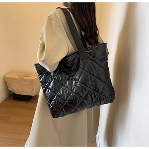Close-up of black quilted puffer tote bag featuring glossy finish and wide nylon straps