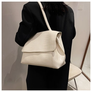 Détail du sac bandoulière blanc crème à texture crocodile sur une veste noire