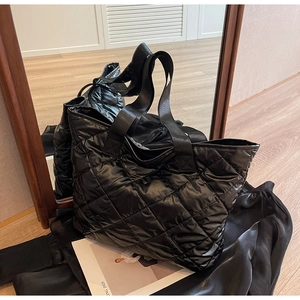 Detailed mirror view of large black quilted tote bag with diamond stitching pattern