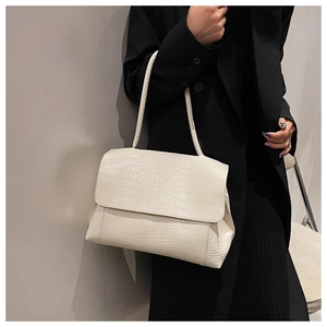 Gros plan sur la texture gaufrée crocodile blanc cassé d'un sac à bandoulière