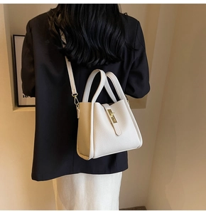 Détail du sac seau en cuir litchi blanc avec fermoir doré et bandoulière réglable